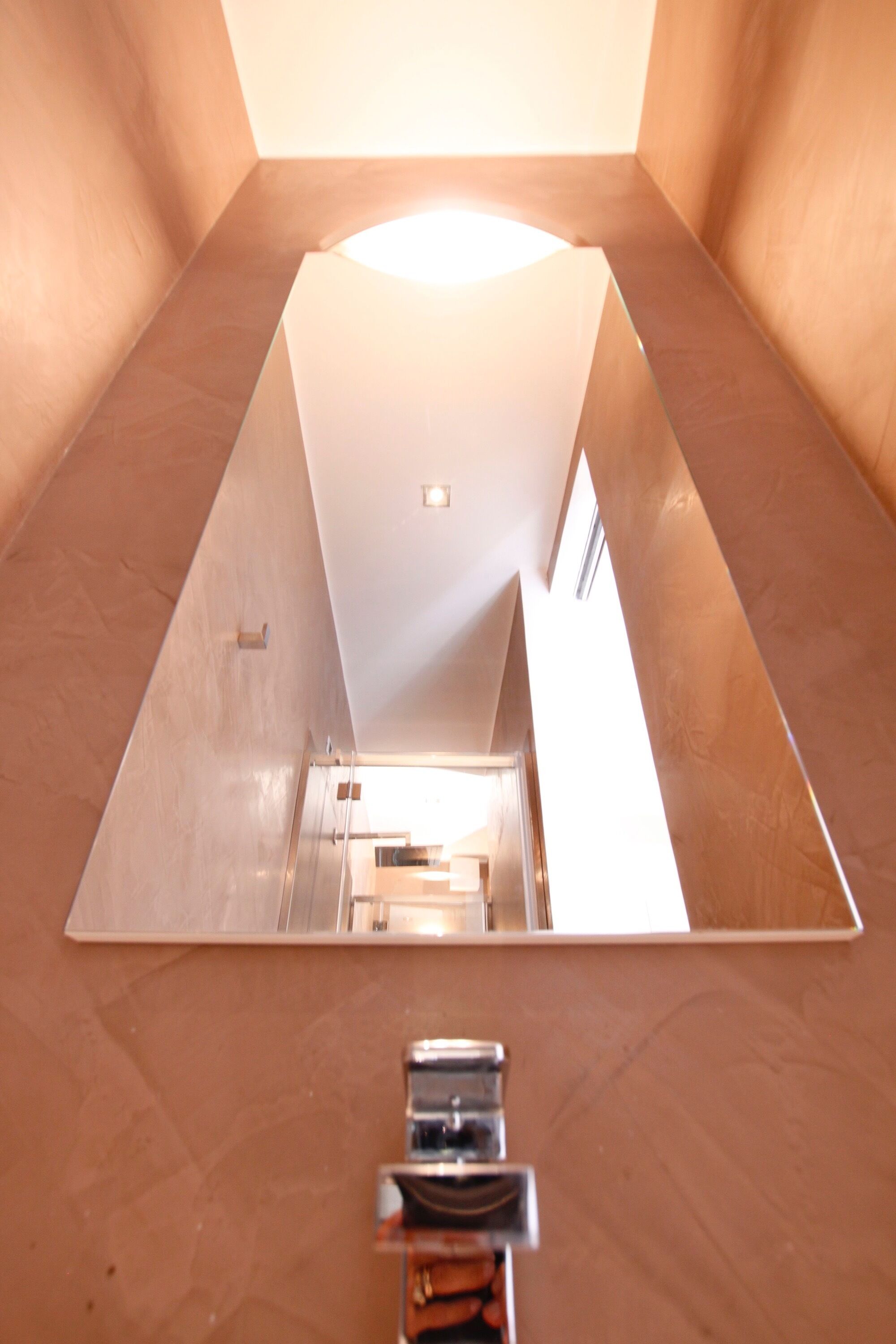 Teto espelhado reflete um corredor com uma porta e um candeeiro.