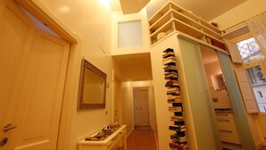 Een smalle gang met een boekenkast, een spiegel en een deur naar een andere kamer.