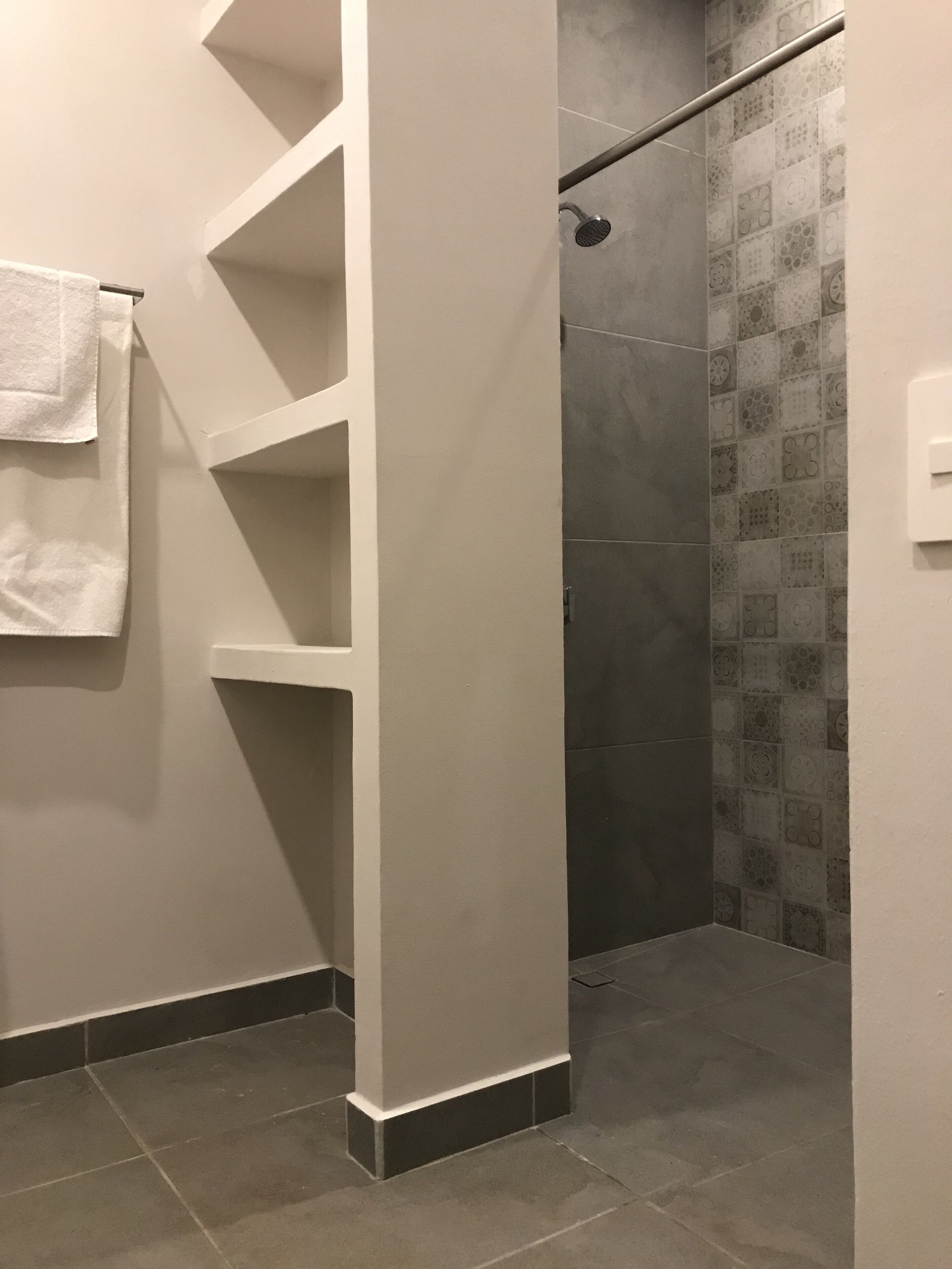 Une salle de bain avec une douche, des murs carrelés et un porte-serviettes.