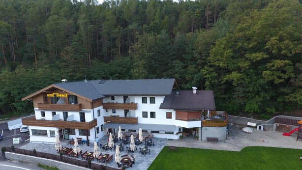 Een hotel met een terras en zitgedeelte buiten, omgeven door een bebost landschap.