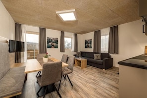 Een moderne woonkamer met een bank, een eettafel en een televisie.