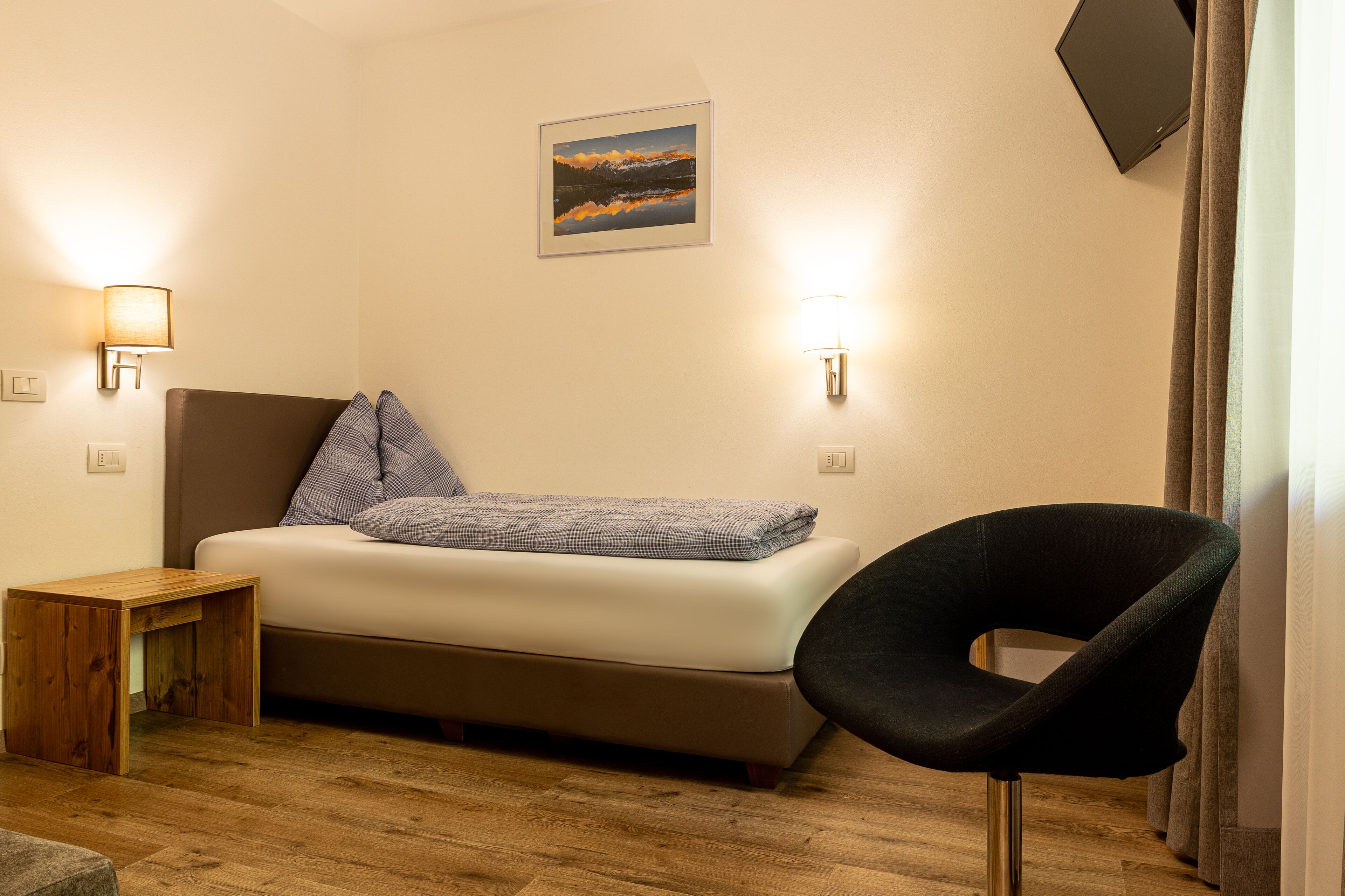 Ein Schlafzimmer mit Bett, Stuhl, Nachttisch und Wandleuchten.