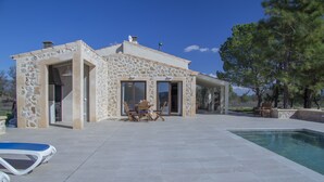 A stone house with a pool, outdoor seating, and a clear sky. - Finca Sa Caseta Biniali (Sencelles)