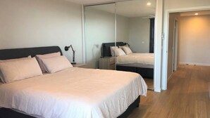 Une chambre à coucher avec un grand lit, une table de chevet, un bureau et un miroir.