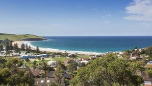 Une ville côtière avec une plage, des maisons et de la verdure.
