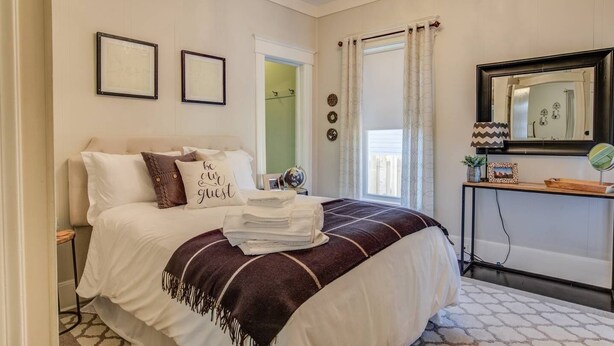 A neatly arranged bedroom with a bed, bedside tables, a mirror, and a view of the outside. - 1893 Classic 4 Blocks From Great Dining & Shops (Colorado Springs)