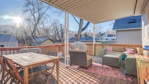 A covered deck with a wooden table and chairs, a grill, and wicker furniture. - 1893 Classic 4 Blocks From Great Dining & Shops (Colorado Springs)