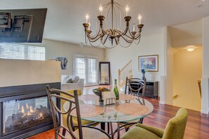 A dining area with a glass table, metal chairs, a chandelier, and a fireplace. - Urban Practicality! 3 Beds, Patios & Dog Friendly (Colorado Springs)