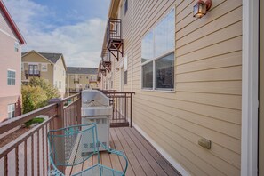 Un immeuble résidentiel doté d’une terrasse en bois, d’un barbecue et d’une chaise en métal.
