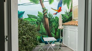 A room with a mural of a tropical scene, a small table, and a chair. - MONKÓ LEMON TROPYCAL APARTMENT (Torremolinos)