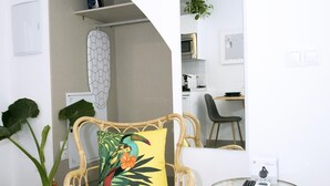 A room with a wicker chair, a round glass table, and a potted plant. - MONKÓ LEMON TROPYCAL APARTMENT (Torremolinos)