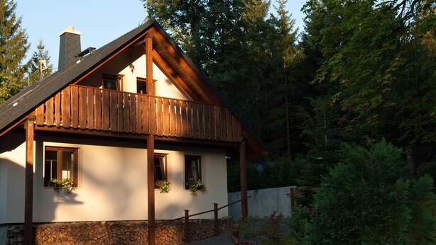 Een chalet met een houten balkon, een stenen fundering en een stenen muur.