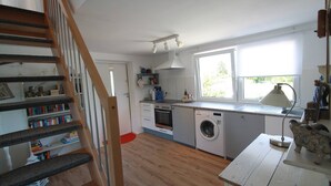 A kitchen with a washing machine, a sink, and a window. - Maisonettewohnung am Privatsee (Karlsruhe)