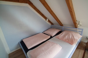 A small, single-bed room with a sloped ceiling and exposed wooden beams. - Maisonettewohnung am Privatsee (Karlsruhe)
