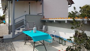 A patio with a table and chairs, a small staircase, and a building in the background. - Maisonettewohnung am Privatsee (Karlsruhe)