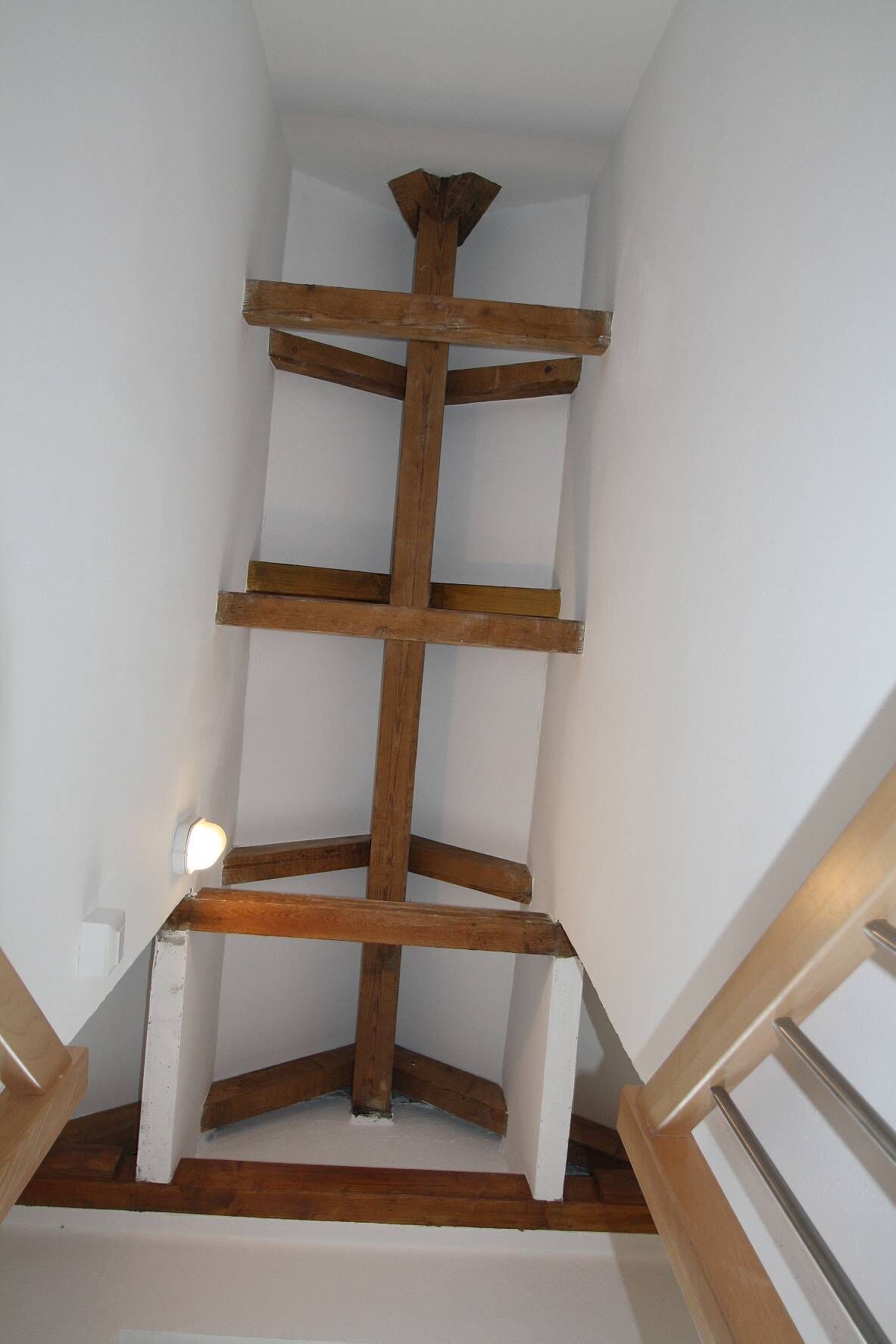 Un escalier en bois, avec des murs blancs et un plafond blanc.