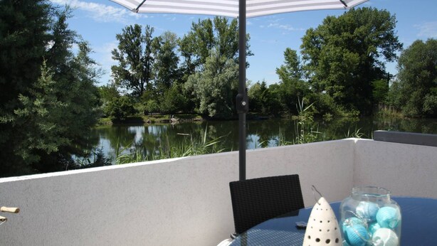 A patio with a table, chairs, and a glass vase with decorative items. - Maisonettewohnung mit großer Terrasse (Karlsruhe)