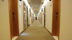 Pasillo de hotel con puertas a ambos lados, piso cubierto de alfombra y un largo corredor.