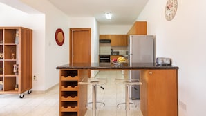 Eine moderne Küche mit Kochinsel, Barhocker, Weinkühler und Kühlschrank.