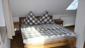 Una camera da letto con un letto in legno, biancheria a quadretti, un comodino e un lucernario.