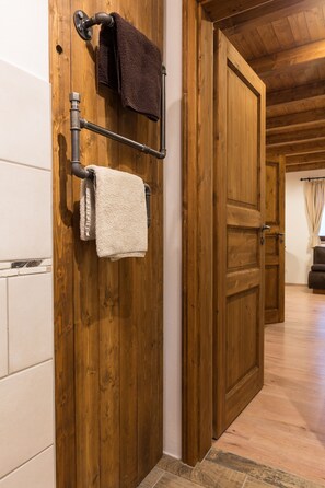 Une porte en bois avec un porte-serviettes sur lequel sont suspendues deux serviettes, un mur en bois et un sol carrelé.