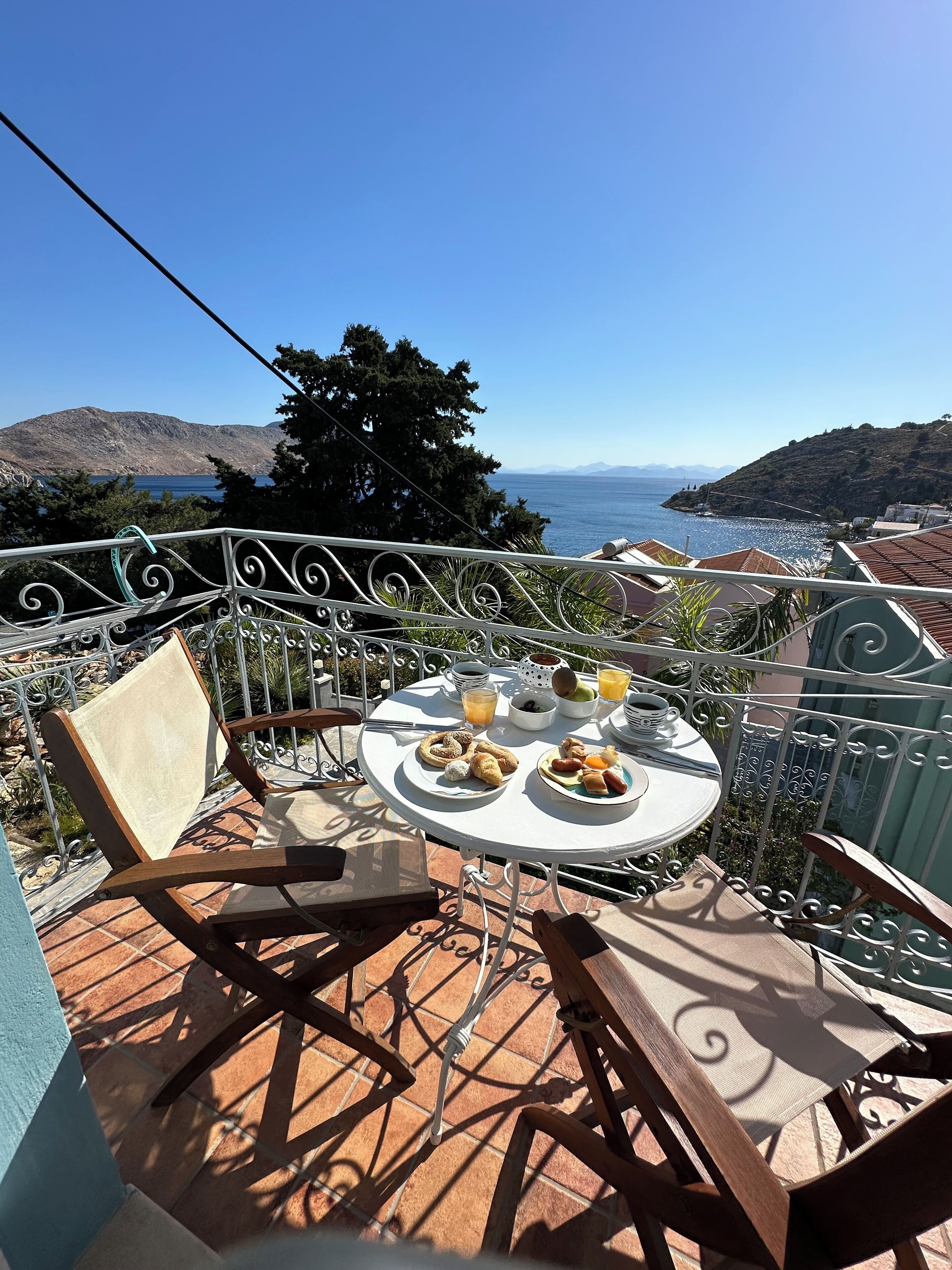 Una terraza con una mesa lista para el desayuno, con vistas a un paisaje costero.