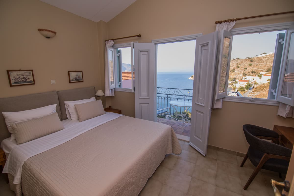 Un dormitorio con una cama grande, una silla y un balcón con vistas al mar.
