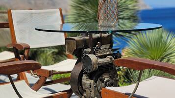 Un espace extérieur aménagé dans un style rustique, avec des chaises en bois et une table dotée d’un socle mécanique.