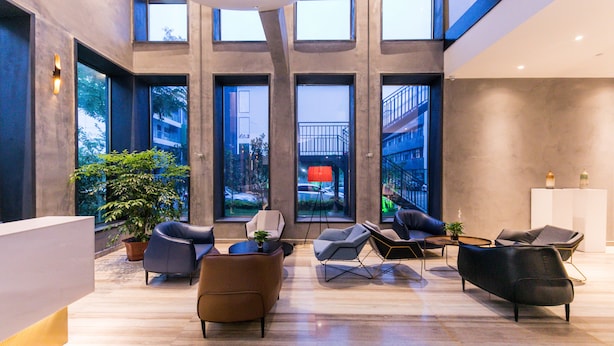 Eine moderne Lobby mit großen Fenstern, einem Empfangsbereich und mehreren Sitzbereichen.