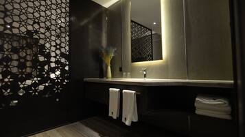 Une salle de bain moderne avec un grand miroir, un parquet en bois foncé et un panneau décoratif mural.