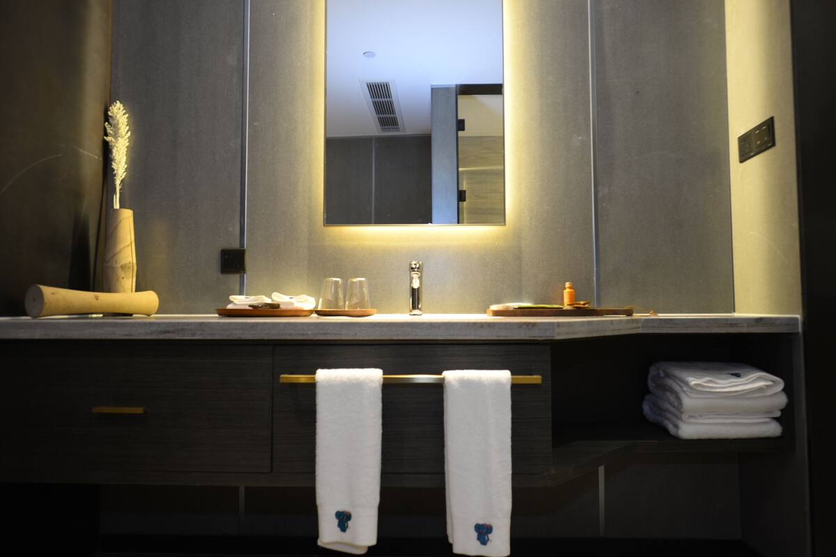 Un bany modern amb un mirall gran, un lavabo i un suport per a tovalloles.