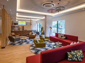 A modern lobby with seating areas, a reception desk, and large windows. - ibis Styles Magdeburg (Magdeburg)