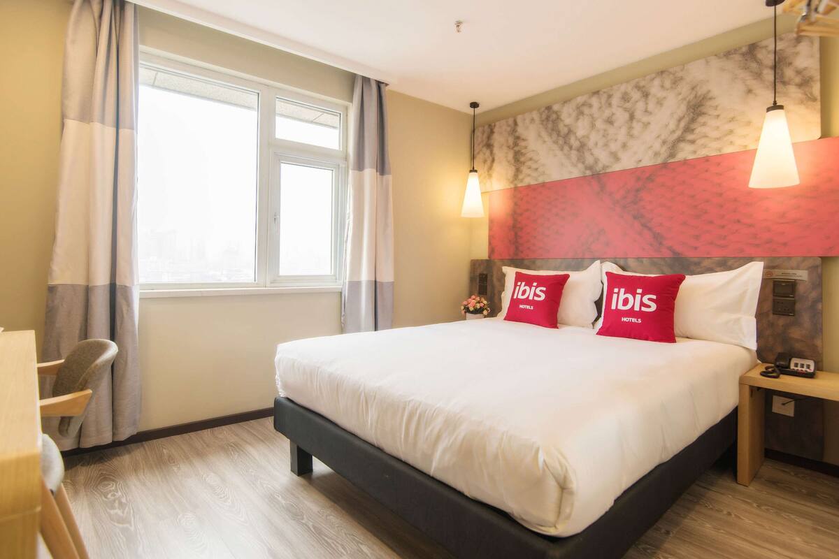 Habitación de hotel con una cama grande, dos mesitas de noche, un escritorio y una silla.