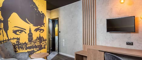 Relax in a stylish room with a comfortable bed, desk, and flat-screen TV, plus a unique cityscape mural and a cozy bench.