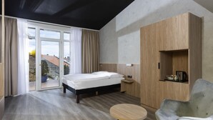 A modern bedroom with a bed, a round wooden table, a grey armchair, and a built-in wooden wardrobe. - ibis Styles Dresden Neustadt (Dresden)