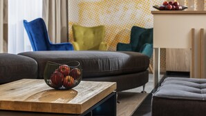 A modern living room with a sofa, a coffee table with apples, and a patterned wall. - ibis Styles Dresden Neustadt (Dresden)
