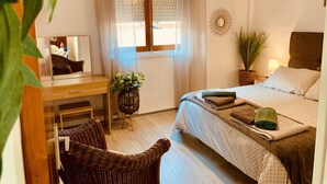 Un dormitorio con cama, escritorio, silla, ventana con cortinas, lámpara colgante y un adorno en la pared.