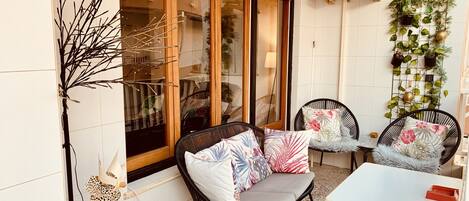 A cozy patio area with wicker chairs, a small table, and a potted plant.