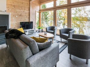 Una sala moderna con sofá, sillones, una mesa de centro y televisor.