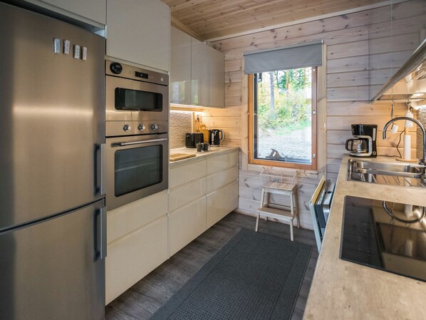 Una cocina moderna con electrodomésticos de acero inoxidable, una encimera de madera y un ventanal con vistas a un paisaje natural.