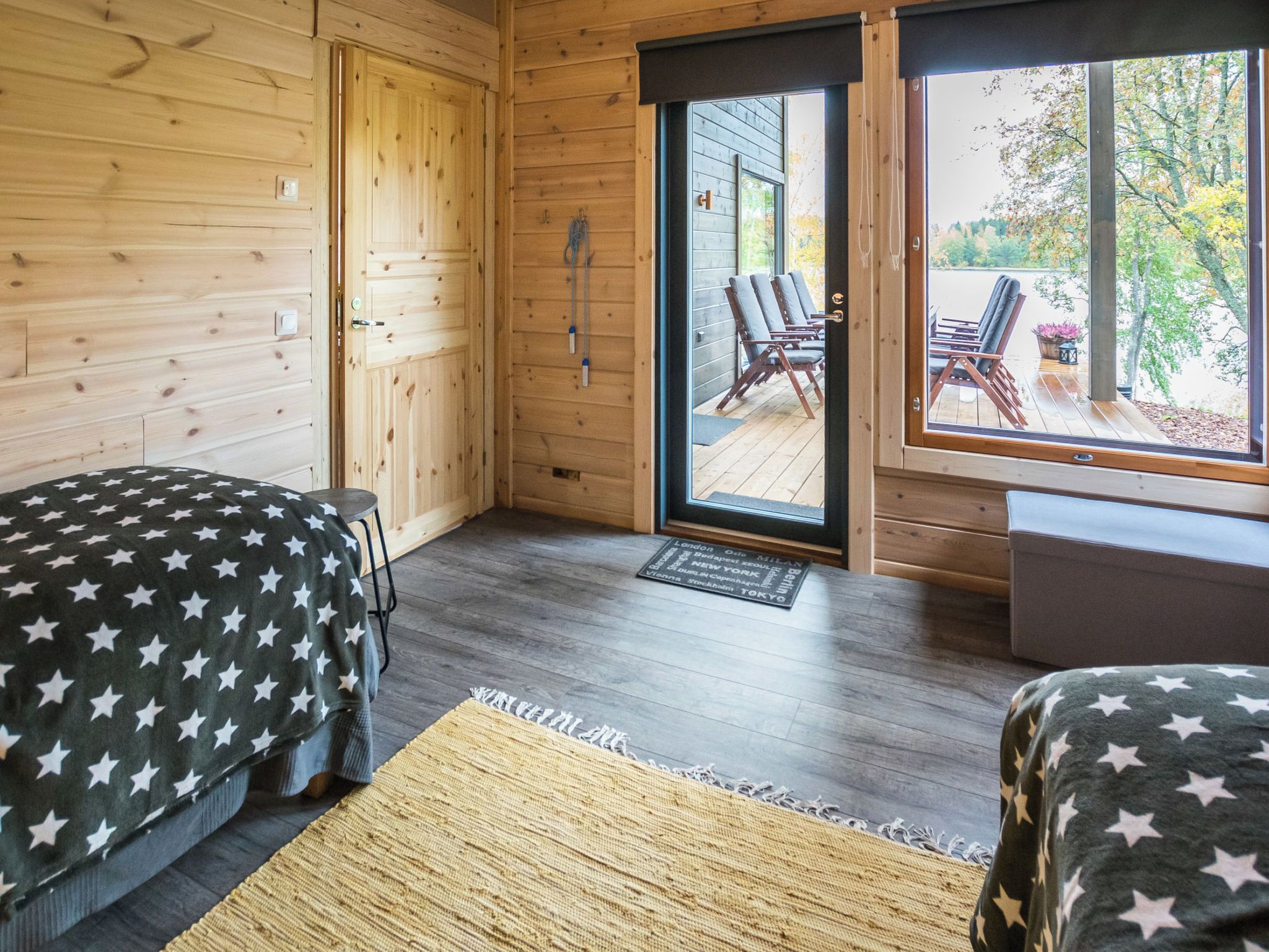 Une chambre avec deux lits, un plancher en bois, une porte donnant sur l’extérieur et une vue sur l’espace aménagé à l’extérieur.