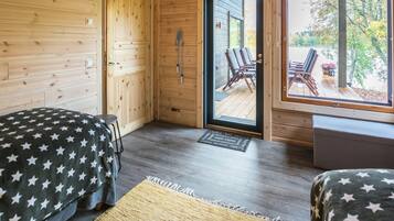 Habitación con dos camas, piso de madera, puerta que da al exterior y vistas a una zona de estar al aire libre.