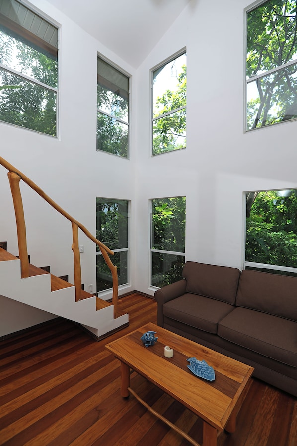Een modern interieur met een houten trap, een bruine bank en een bijzettafeltje met decoratieve objecten.