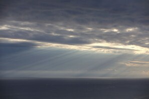 A view of the ocean under a cloudy sky with sunlight filtering through.