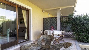 An outdoor patio with wicker furniture, a glass door leading to an interior room, and a table with chairs. - Aria Di Vacanza - Mirtillo COD 9 (Olbia)