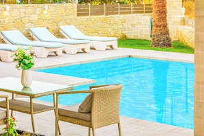 A pool area with lounge chairs and a table.