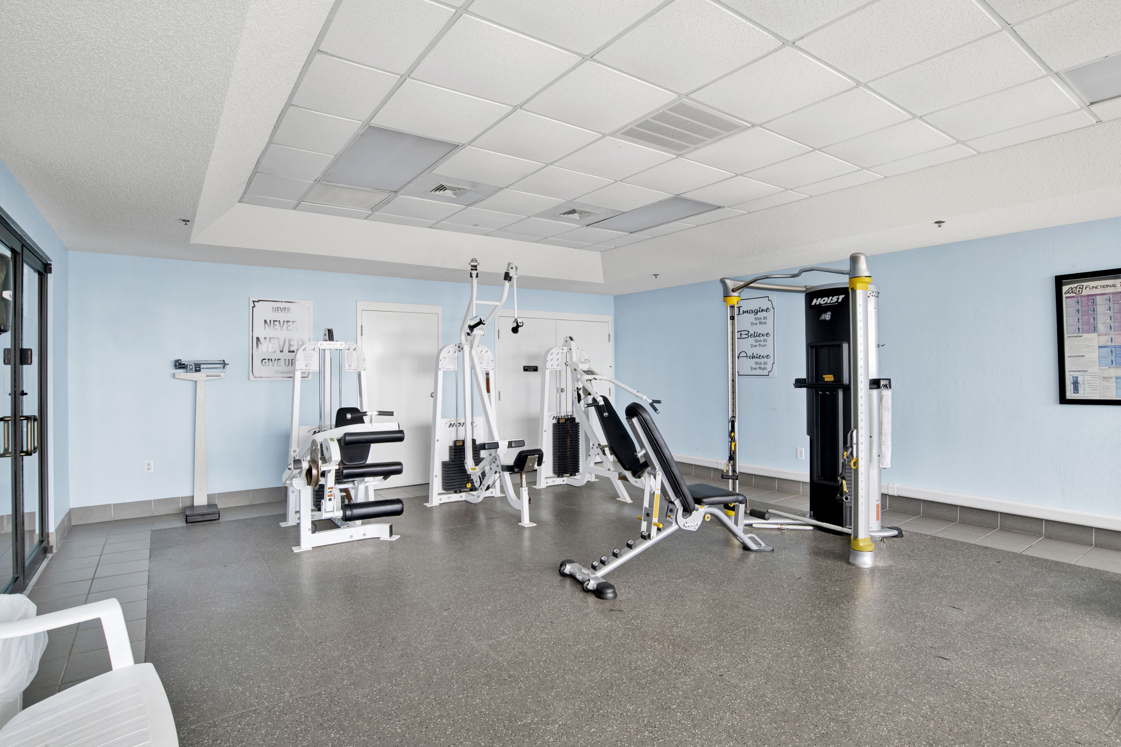 A gym with various exercise equipment, a scale, and motivational posters on the walls.