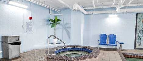 Un área de spa con un jacuzzi, un bote de basura, un banco y una planta.