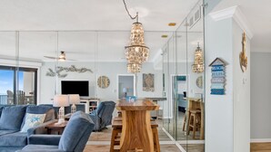 Uma sala de estar moderna com uma janela grande, uma mesa de jantar de madeira e um candelabro.