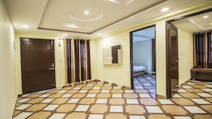 A hotel room with a checkered floor, a wooden door, and a mirror on the wall. - Comfort Homestay (Dalhousie)